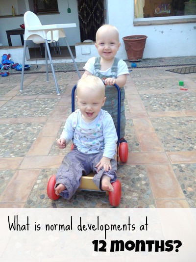 A baby pushing another baby in a walker